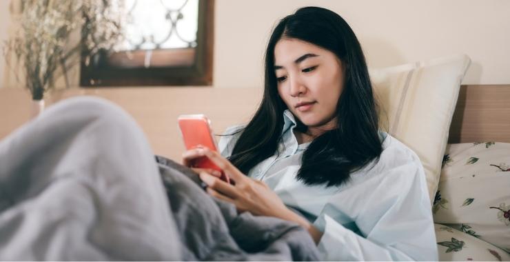 Woman in bed looking at her cell phone