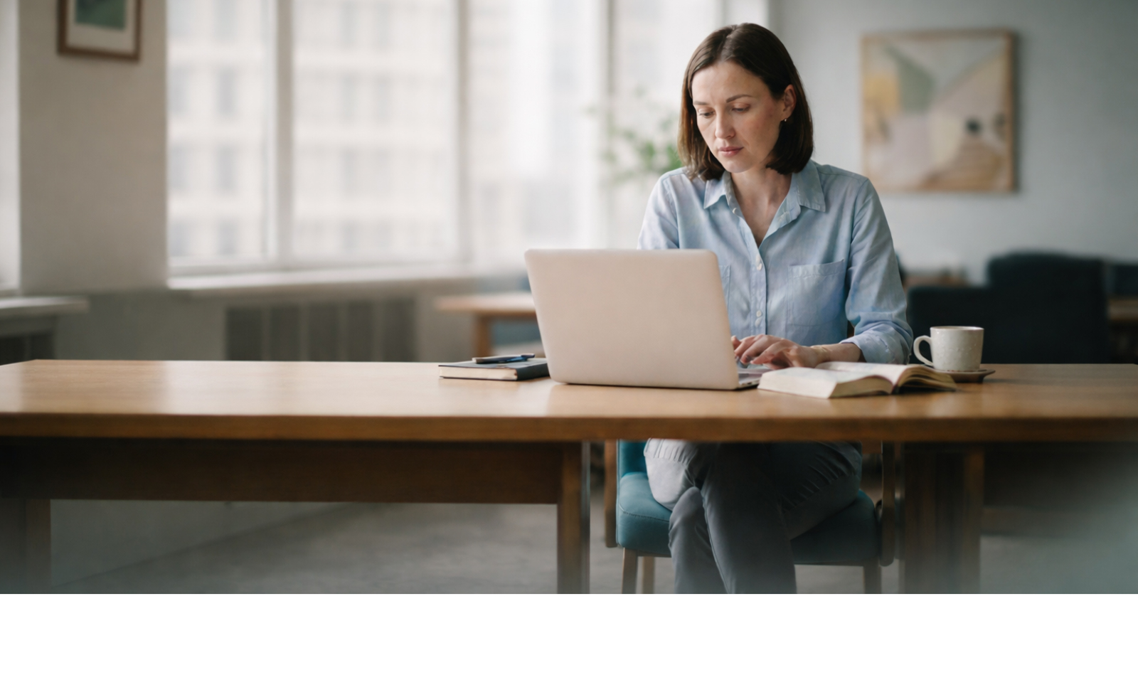 Young woman sitting at table working on laptop.
