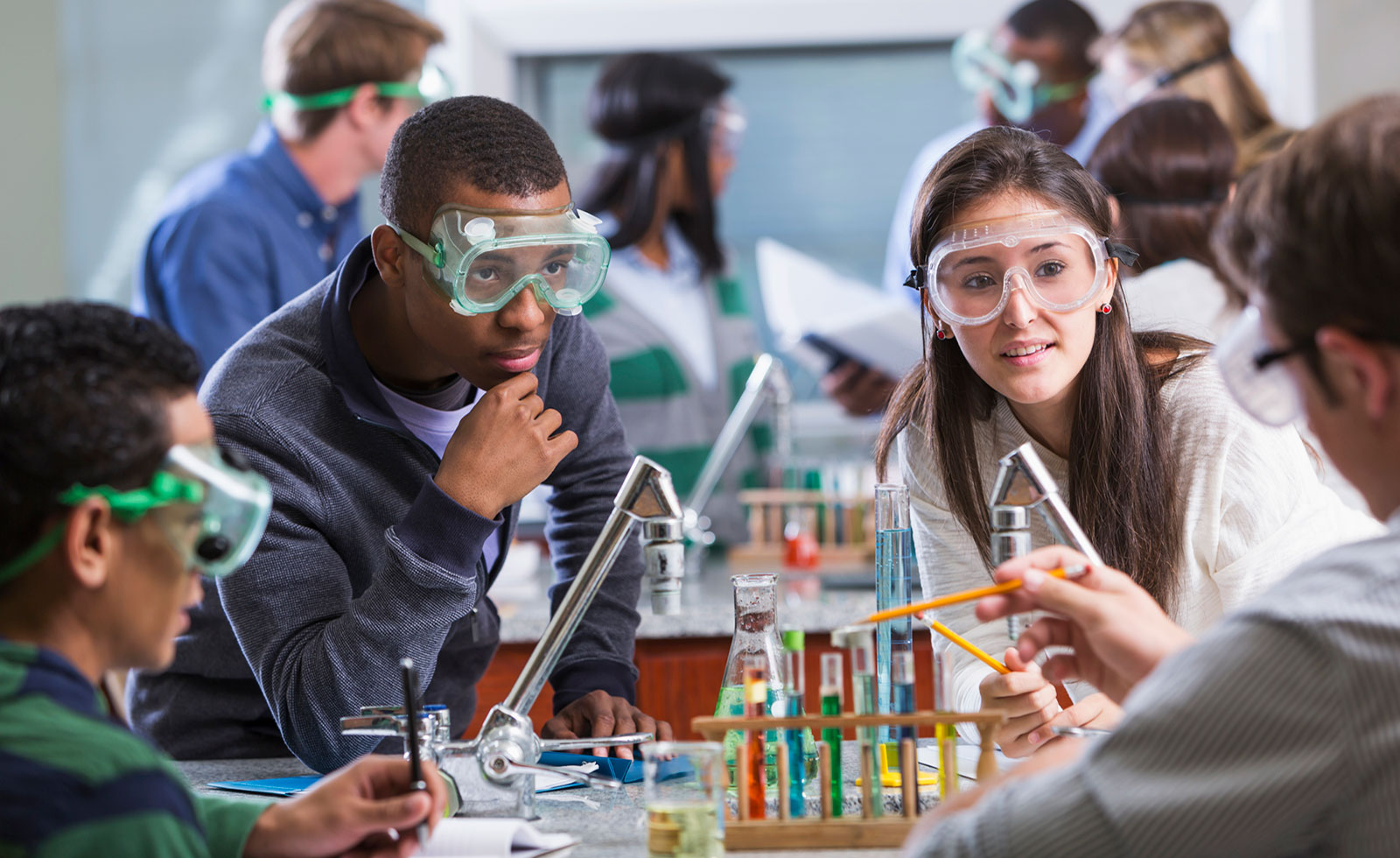 High school teacher demonstrates science experiment to students.