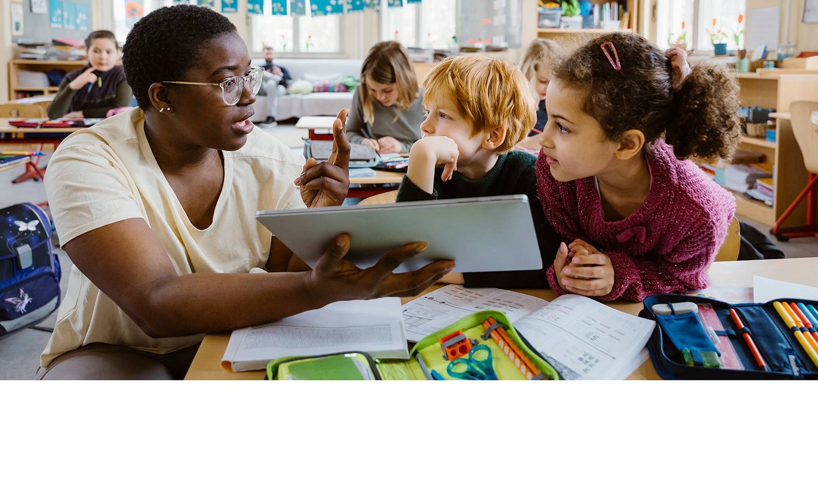 Teacher assisting students with using their tablets in class.