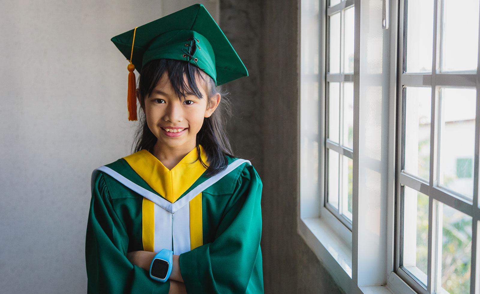 Elementary school-aged Asian child wearing graduation cap and gown.