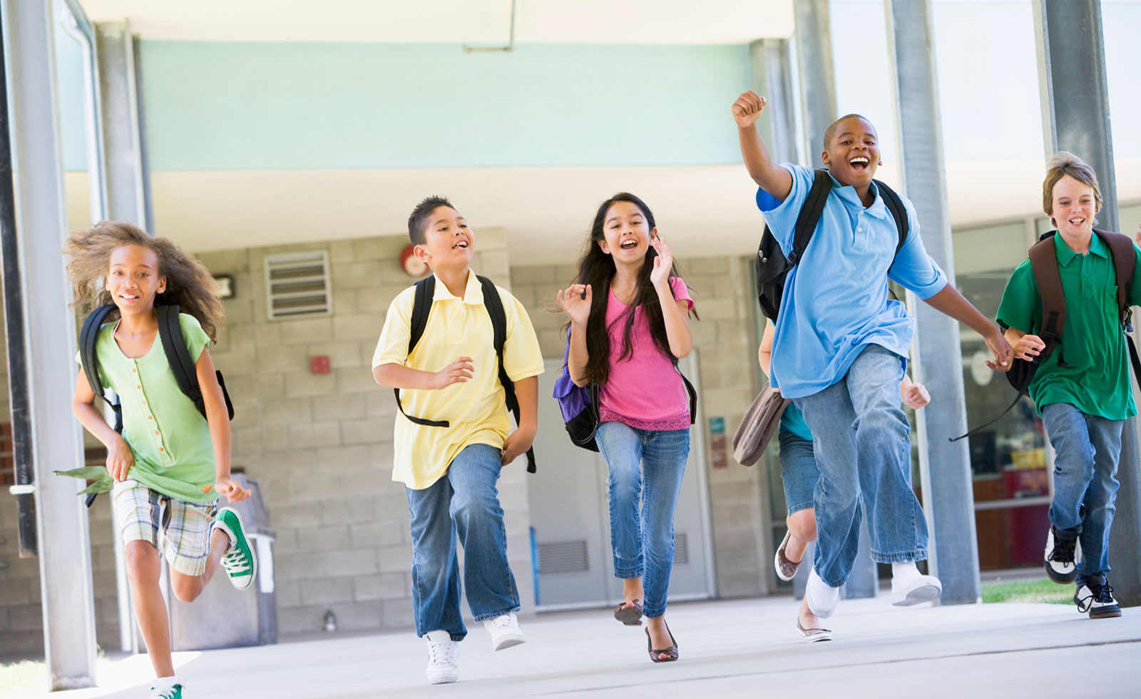 Group of elementary school students running out of school.
