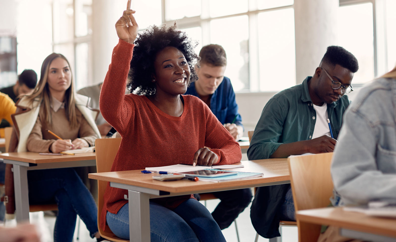 High school student raising hand to answer question in class.
