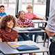 Elementary school students smile at teacher in class.