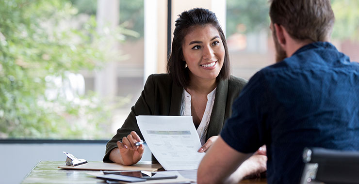 Latina woman handing a piece of paper to a man in her office