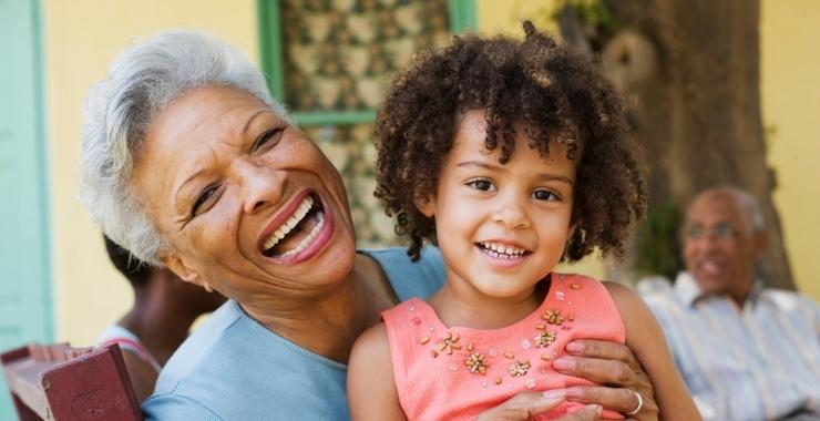 Grandmother holding granddaughter while laughing and smiling.