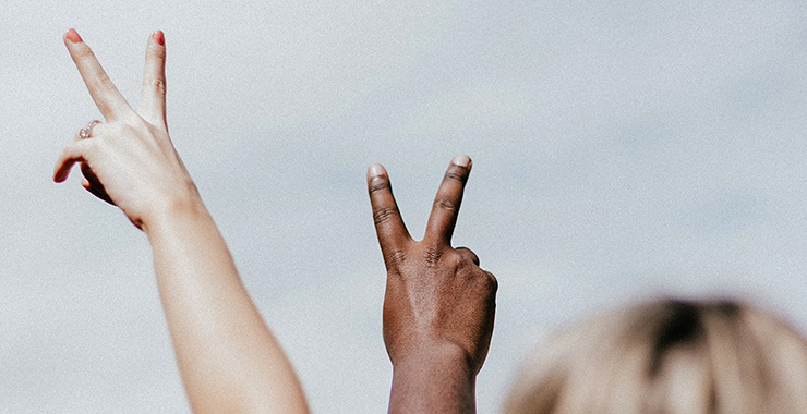 people with arms extended showing peace signs